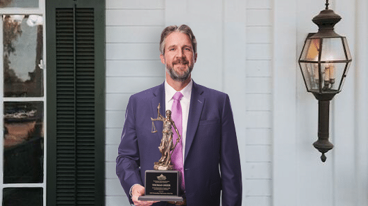 Thomas Greer standing in front of office with TTLA Award
